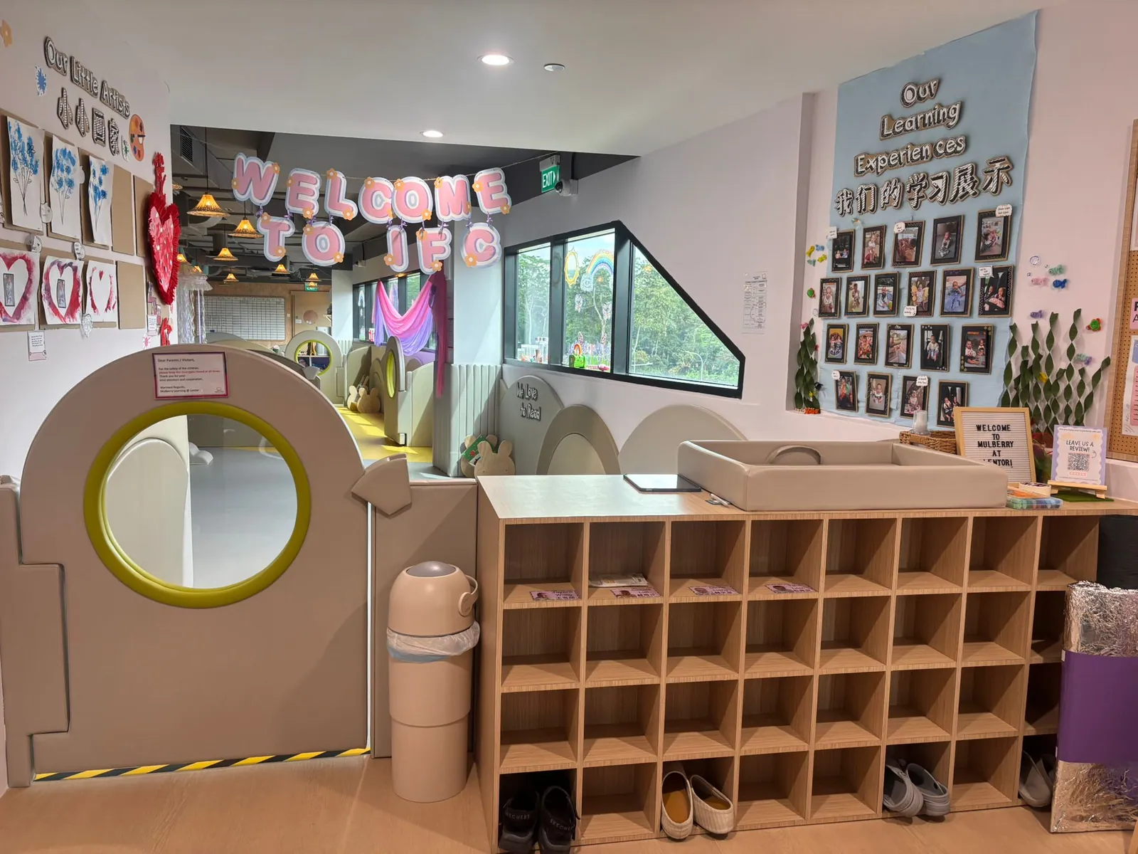 The infant care entrance with Welcome to IFC bunting, cubbies and Our Learning Experiences photo wall